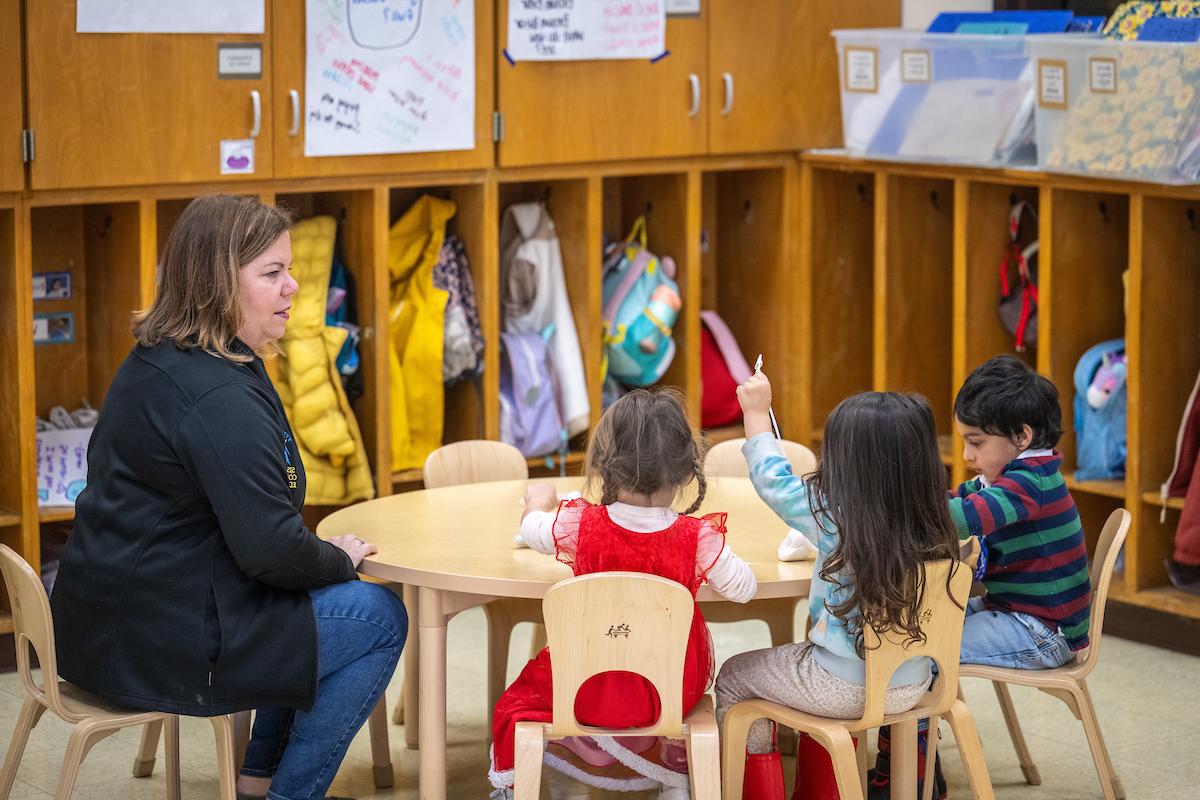 a teacher sitting with a few children students 